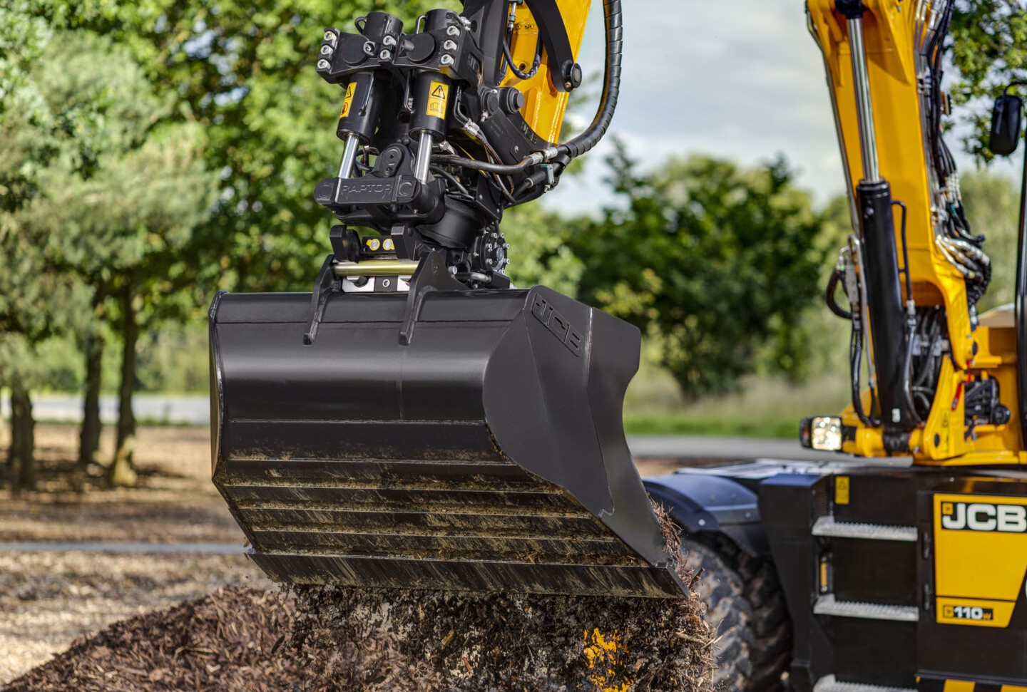 JCB excavator bucket attachment releasing soil and debris during operation